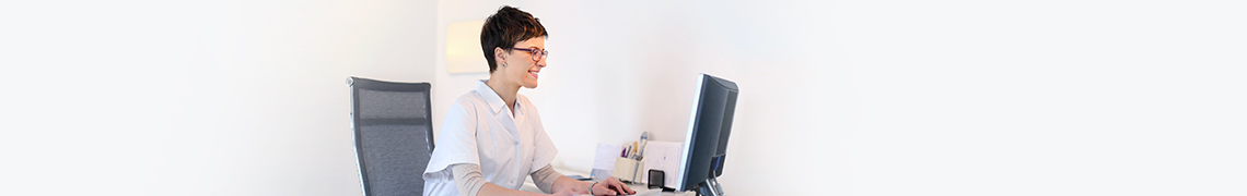 Smiling woman sits at laptop using the RALS System.